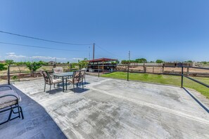 Un'area patio con tavolo e sedie, una zona salotto coperta e vista su un edificio e un paesaggio.