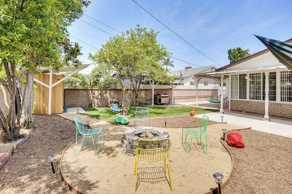 A backyard with a fire pit, outdoor chairs, and a covered patio area. - 12 Mi to Dtwn LA: Family Home w/ Patio + Yard! (Downey)