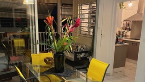 A dining area with a glass table, yellow chairs, and a red rug. - Appart Anse à l'Ane, Les Trois Ilets, with panoramic view 300 m from the sea (LES TROIS ILETS)