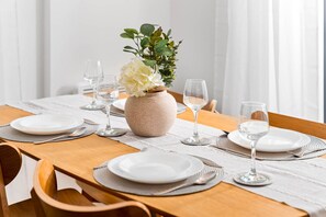 A dining table set with white plates, silverware, and wine glasses, centered with a vase of white flowers. - Luxury 2 Bedroom with Balcony* Fast Wi-Fi* Netflix (Birmingham)