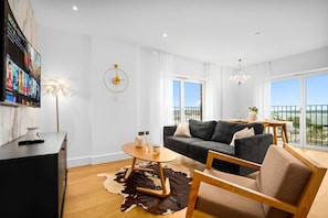 A modern living room with a sofa, a coffee table, and a TV mounted on the wall.