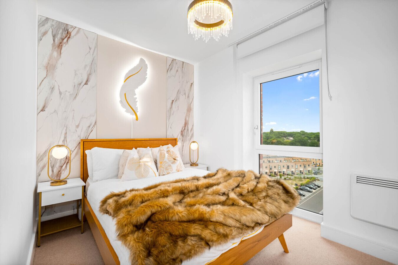 A bedroom with a large bed, marble walls, a feather light design, and a view of a cityscape.