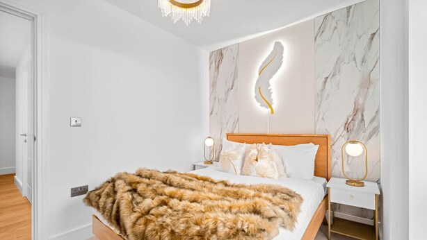 Ein Schlafzimmer mit einem Bett, einer Wanddekoration aus Federn und zwei Nachttischlampen.