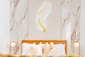 A bedroom with a marble wall, a wooden headboard, and a decorative feather.