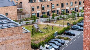 Ein mehrstöckiges Wohngebäude mit Parkplatz und kleinem Spielplatz.