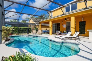A pool area with a covered section, lounge chairs, and a yellow building. - Luxury 2850sf Rental | Water + Conservation Views | Near Clubhouse | Gated (Davenport)