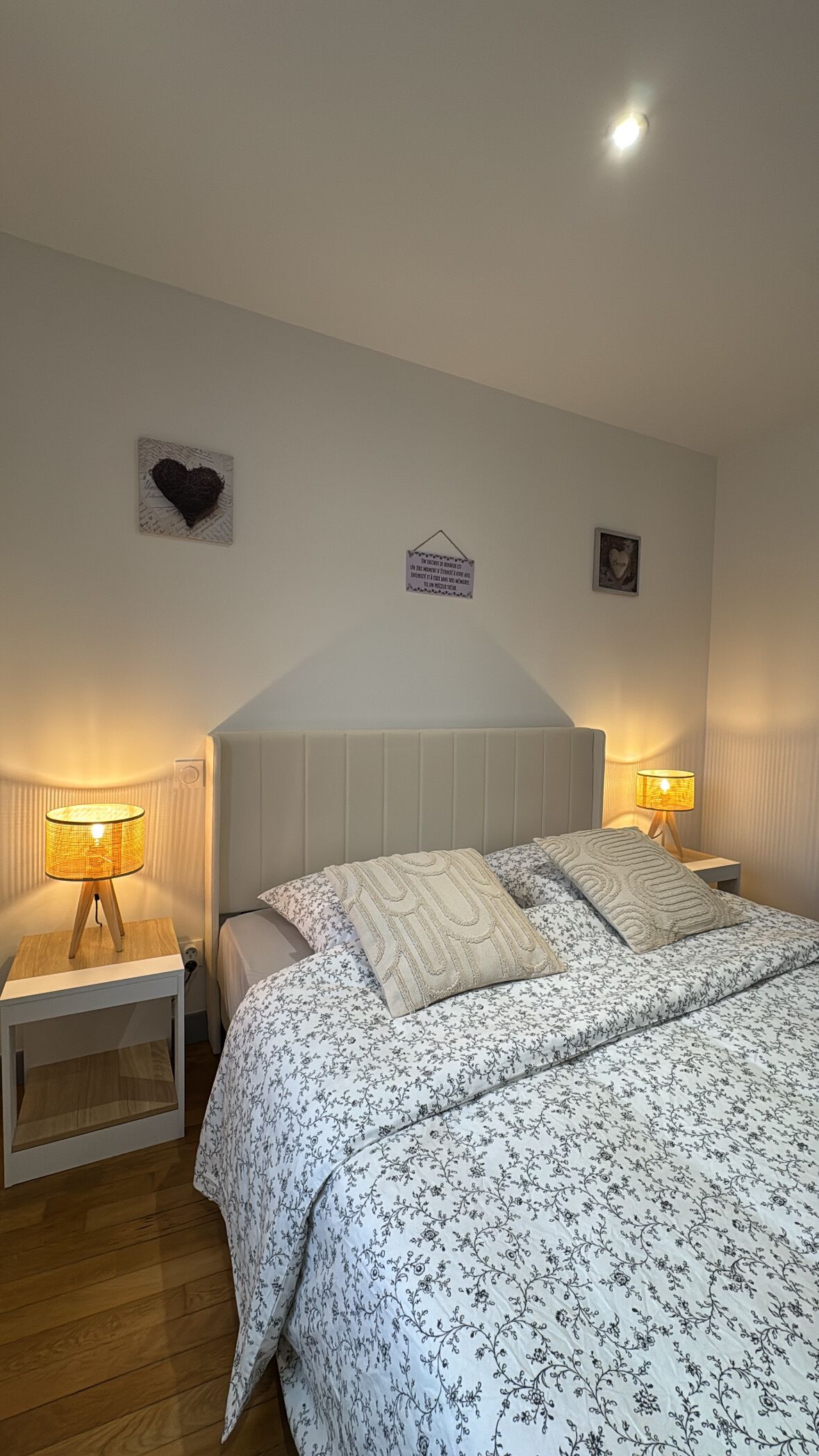 Un dormitorio con una cama, dos mesitas de noche y adornos en la pared.