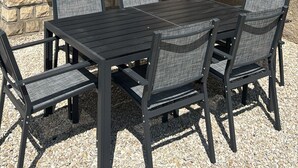 An outdoor patio with a table and chairs, a large umbrella, and a stone wall.