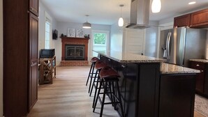 A spacious kitchen with a central island, bar stools, and a fireplace. - Family-Friendly 3BR Historic Home – Walk to Keene Central Square & Trails! (Keene)