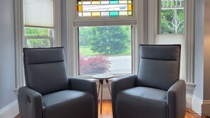 A room with two leather chairs facing a large window with a stained glass design. - Family-Friendly 3BR Historic Home – Walk to Keene Central Square & Trails! (Keene)