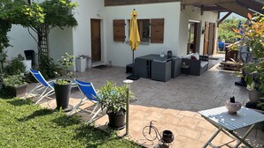 Un patio con muebles exteriores, un paraguas amarillo y vistas a la montaña.