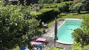 Un patio trasero con piscina, una terraza de madera y una silla.