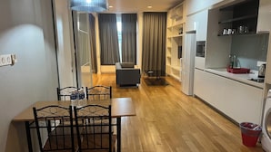 A modern kitchen with white cabinets, a built-in oven, and a refrigerator. There is a dining area with a wooden table and chairs. - Platinum Suites Kuala Lumpur by Skyline (Kuala Lumpur)
