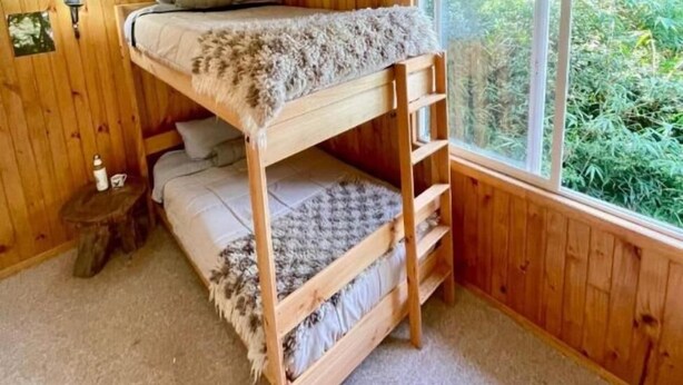 Ein Stockbett in einem Holzraum mit Fenster und kleinem Tisch.