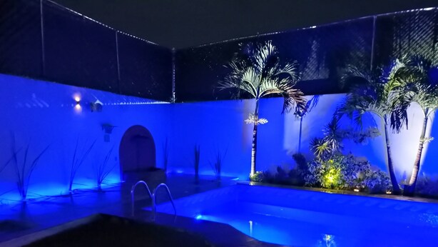 A swimming pool with a blue-lit deck, surrounded by palm trees and tropical plants. - HOUSE WITH SWIMMING POOL IN CUAUTLA DOWNTOWN (Cuautla)
