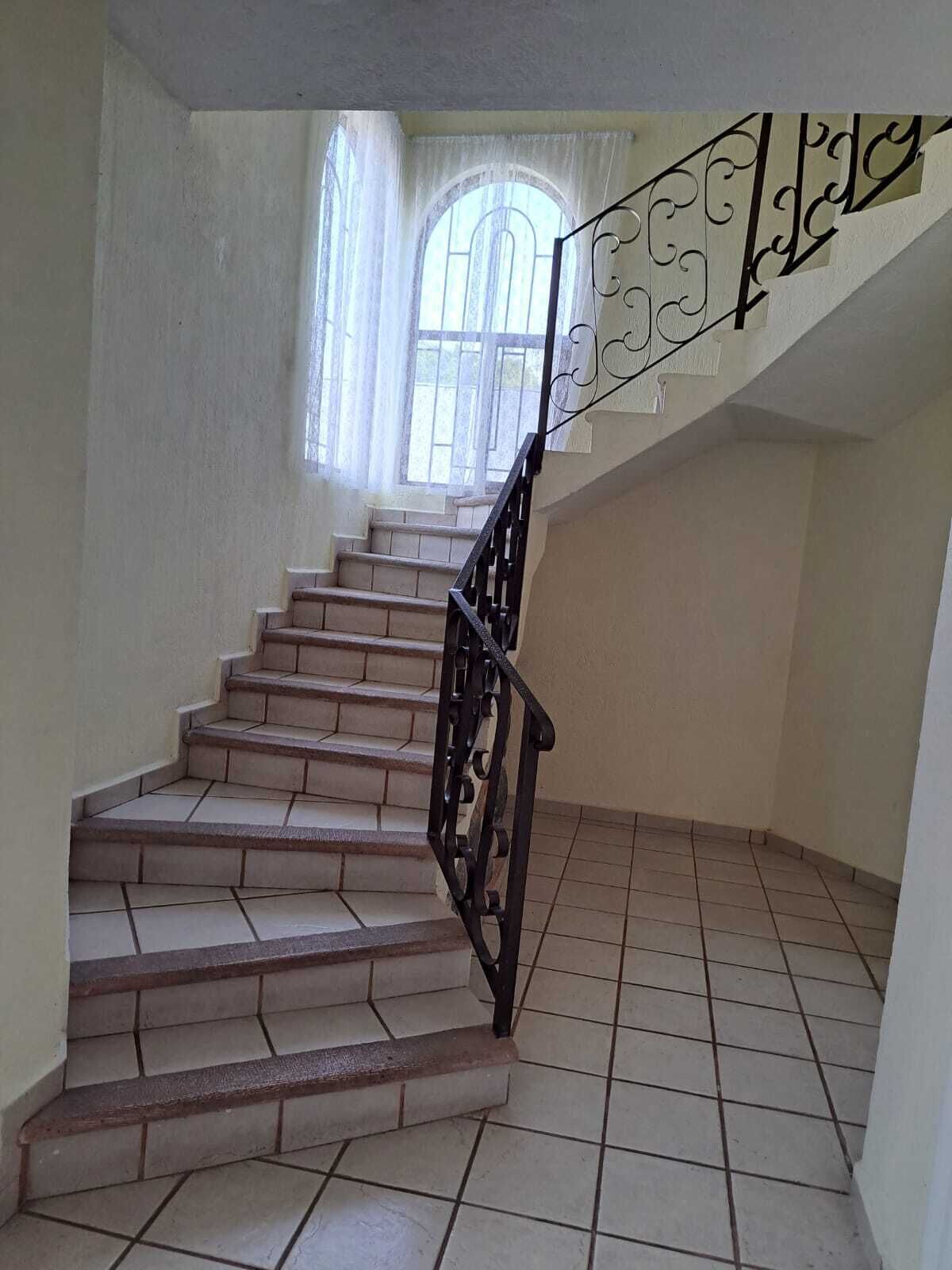 Eine Treppe mit schwarzer Metallgeländer, die zu einer Zwischenebene führt.