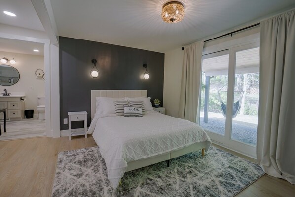 Un dormitorio con cama, mesitas de noche, cortinas en la ventana y vistas al exterior.