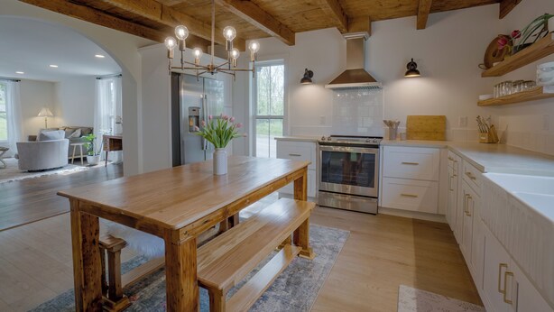 Una cocina moderna con vigas de madera, una isla central y electrodomésticos de acero inoxidable.