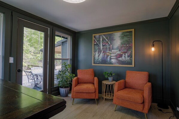 Una habitación con dos sillones anaranjados, una mesa de madera, una planta en maceta y un cuadro en la pared.