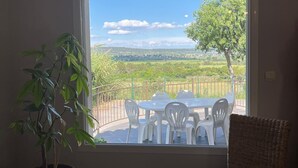 A room with a large window overlooking a patio with a table and chairs. - Family home between the sea and the Cevennes (Calvisson)