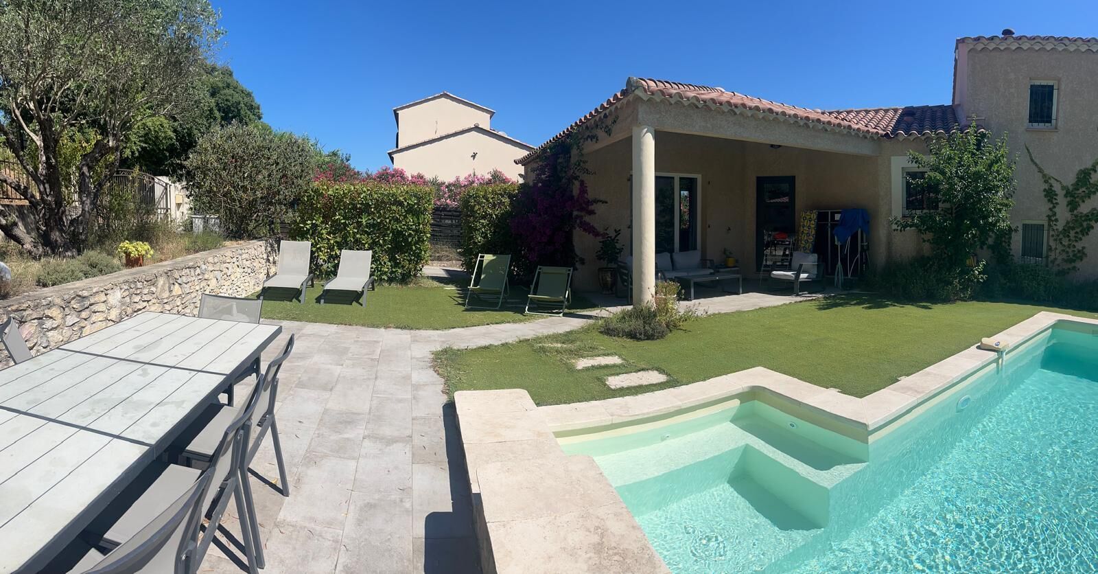 A poolside area with a pool, outdoor seating, and a stone wall.