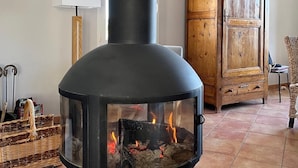 A modern living room with a black wood-burning stove, a wooden cabinet, and a wicker basket. - Family home between the sea and the Cevennes (Calvisson)