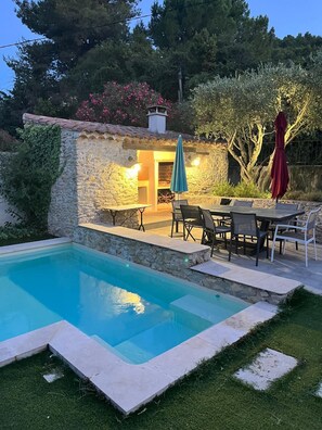 Ein Steinhaus mit Pool, Sitzgelegenheiten im Freien und einer Feuerstelle.
