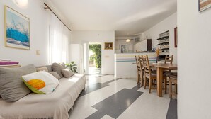 Una sala de estar moderna con un sofá, un comedor con sillas de madera y una cocina al fondo.