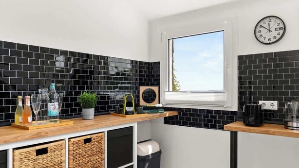 A modern kitchen with black tiled backsplash, wooden cabinets, and a window providing natural light. - MOLA Apartments-Style & Flair (Wetter (Ruhr))