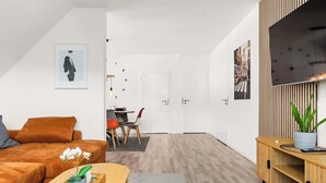 A modern living room with a sofa, coffee table, and a TV on a wooden stand. - MOLA Apartments-Style & Flair (Wetter (Ruhr))