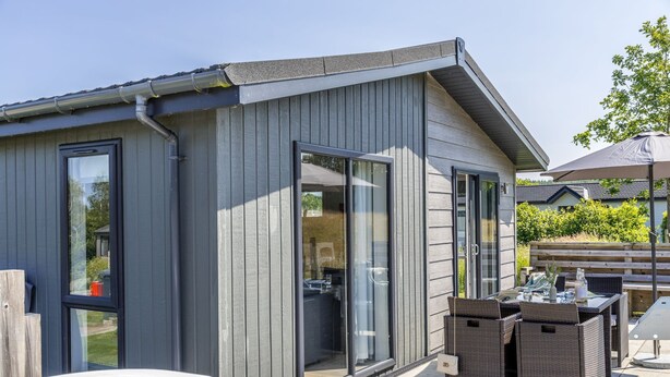 A modern outdoor patio area with a hot tub, wicker furniture, and a sliding glass door leading to a covered outdoor space. - Poppy, 5 Roadford Lakes Lodges  -  a lodge that sleeps 4 guests  in 2 bedrooms (Roadford Lake)