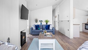 A modern living room with a sofa, coffee table, and fireplace. - Poppy, 5 Roadford Lakes Lodges  -  a lodge that sleeps 4 guests  in 2 bedrooms (Roadford Lake)
