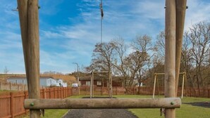Et legesæt i træ i en park under en blå himmel.