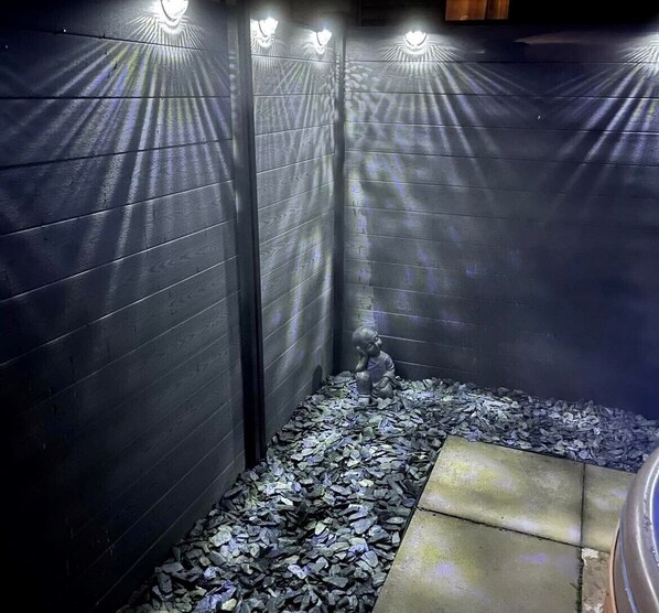 A narrow, dimly lit corridor with a small statue of a child on a gravel path.