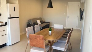 Una cocina moderna con zona de comedor, que incluye una mesa de madera, sillas de metal y una lámpara colgante.