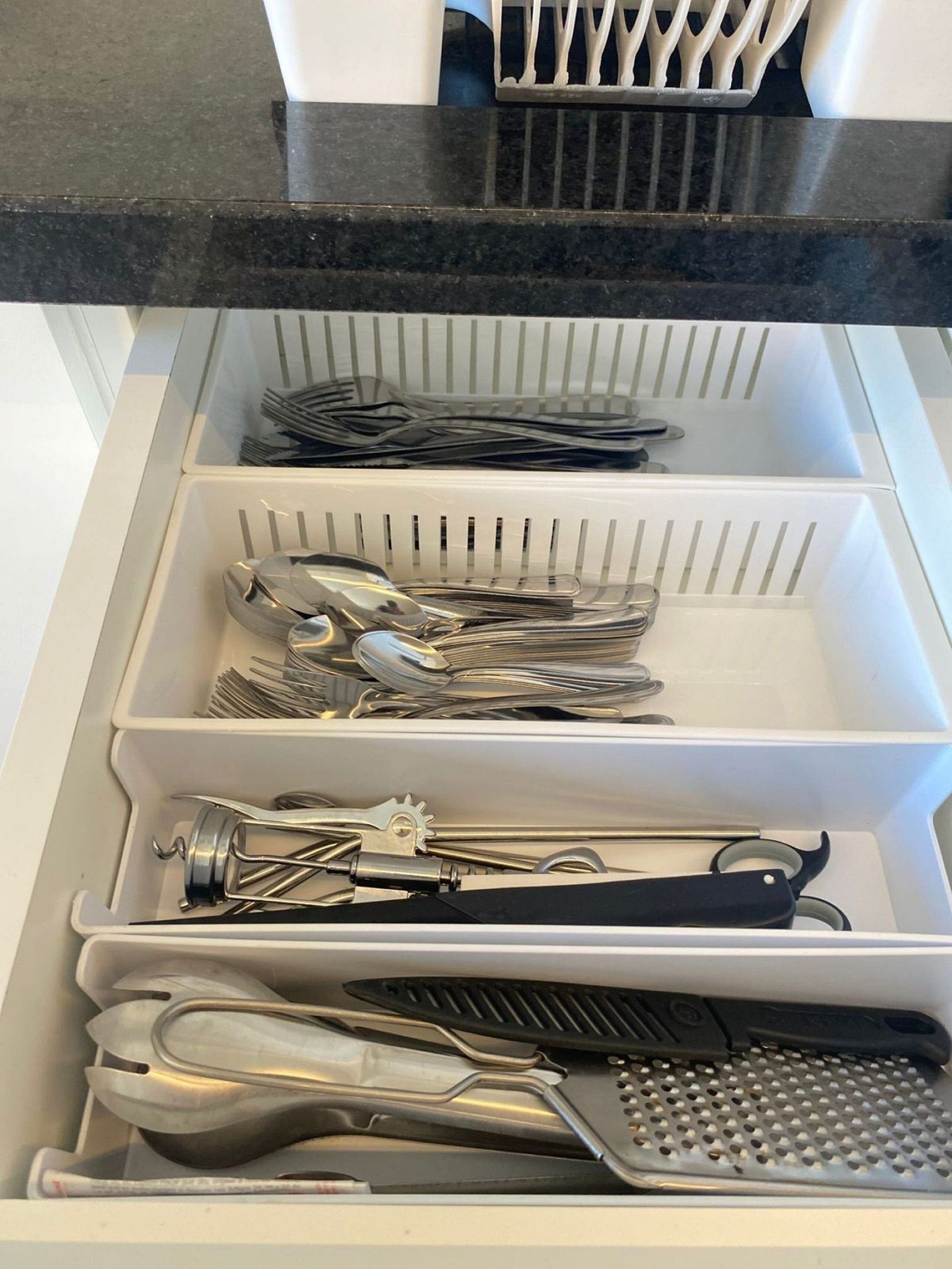 A drawer with compartments containing various kitchen utensils.