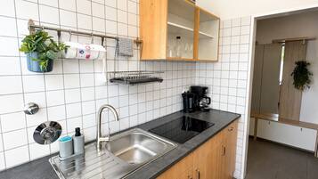 Eine moderne Küche mit Spüle aus Edelstahl, Holzschränken, einer schwarzen Arbeitsplatte und einer Kaffeemaschine.
