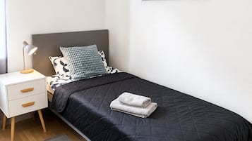 Ein Schlafzimmer mit einem Bett, einem Nachttisch, einer Lampe und einem Bild einer Brücke.