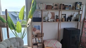 Una sala de estar con un sofá, una mesa de centro de madera, una estantería y un televisor.