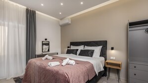 Une chambre d’hôtel moderne équipée d’un lit queen-size, d’une table de chevet, d’un miroir, d’un climatiseur et d’une armoire.