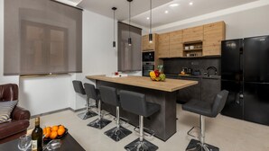 Une cuisine moderne dotée d’un îlot central, de tabourets de bar, d’un réfrigérateur et d’un coin repas avec un canapé.