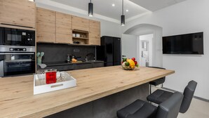 Une cuisine moderne avec des meubles en bois, un réfrigérateur noir, un four encastré et un îlot central en bois doté de sièges.