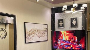 A modern living room with a fireplace, a round glass table, and a sofa. - Home-Away FromHome@ Trees  Residences QC (Quezon City)