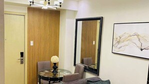 A modern living room with a grey sofa, a round coffee table, and a chandelier. - Home-Away FromHome@ Trees  Residences QC (Quezon City)