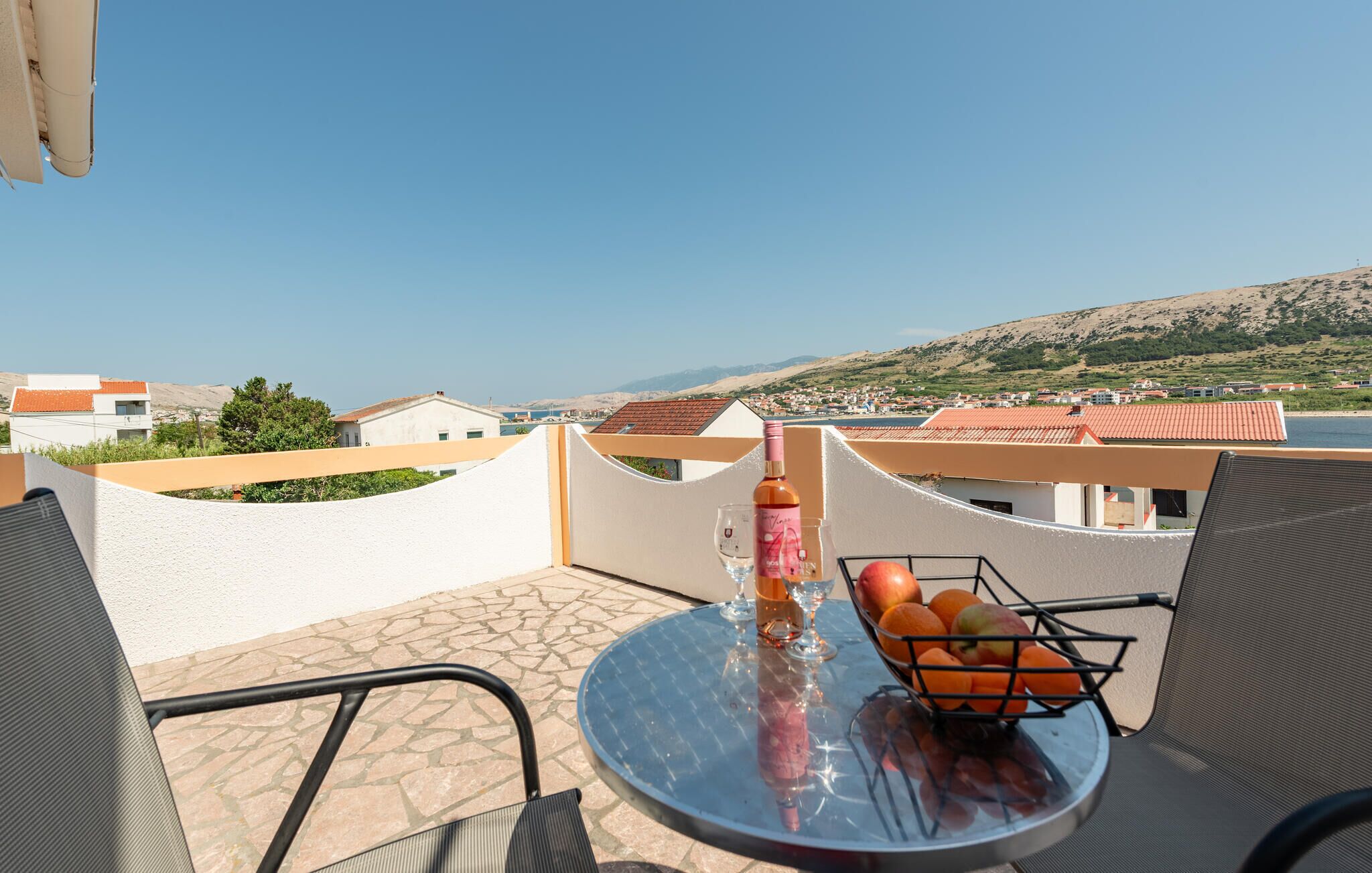 Ein Balkon mit Tisch, einer Flasche und einer Obstschale.