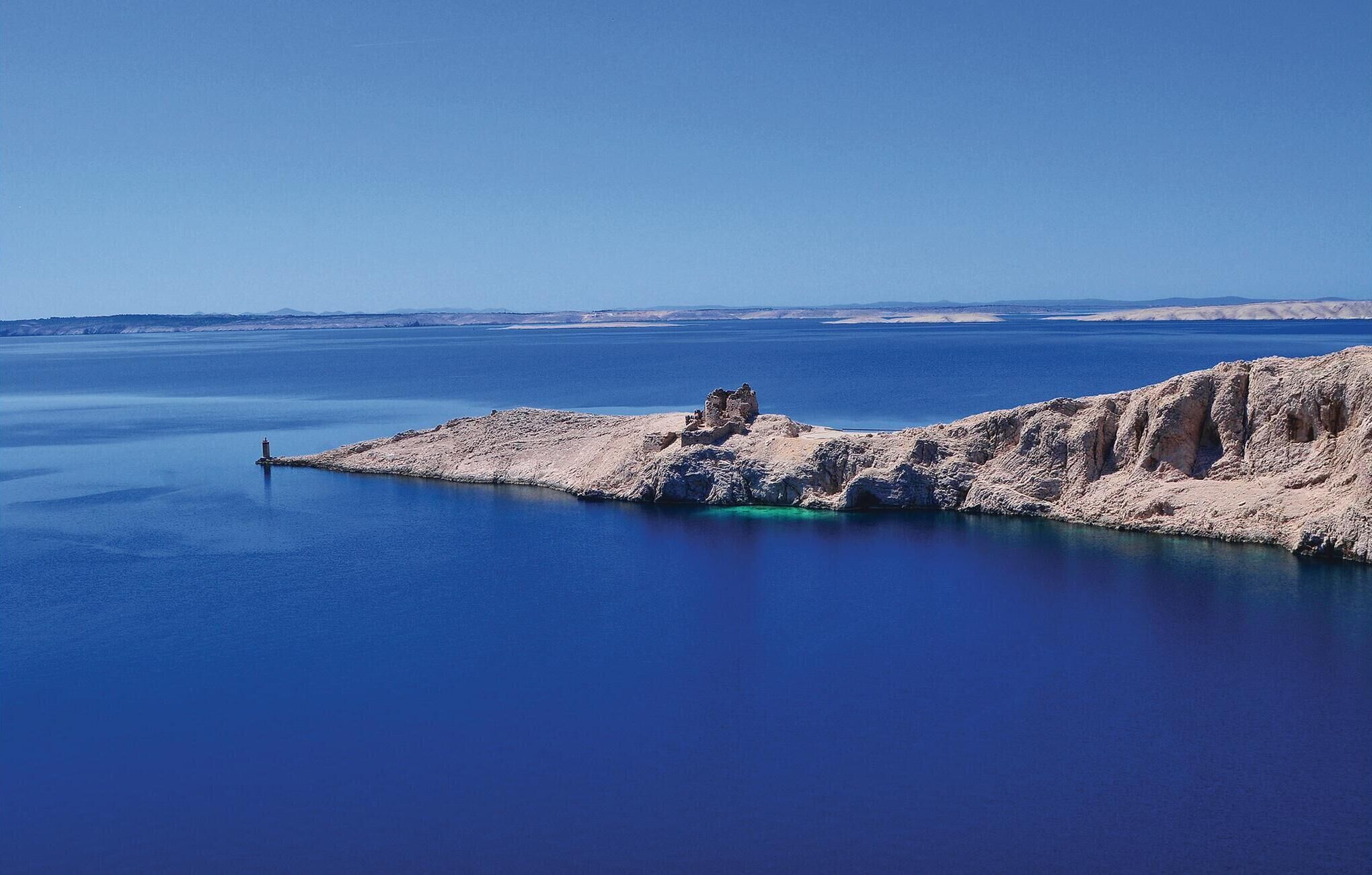 A coastal landscape with a rocky outcrop and a lighthouse.