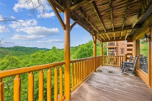 Une terrasse en bois dotée d’une rambarde, offrant une vue sur un paysage verdoyant et luxuriant.