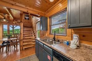 L’intérieur d’une cabane en bois comprend un espace cuisine, un coin repas et un escalier menant à un niveau supérieur.
