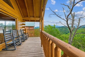 Une terrasse en bois avec des bancs, donnant sur un paysage boisé.