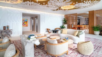 Ein modernes Wohnzimmer mit einem weißen Sofa, Korbmöbeln und einem Teppich mit roten und weißen Mustern.